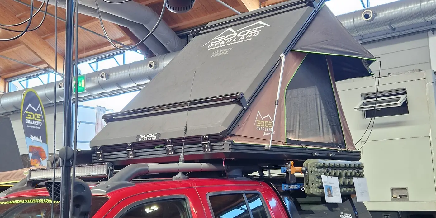 Aufgeklapptes Aluminium-Hartschalen-Dachzelt auf einem roten Pickup, Unterseite mit Wabenplatte sichtbar