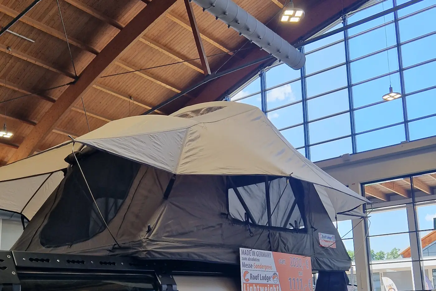 Klassischer Land Rover Defender mit Softshell-Dachzelt und darueber gespannter Markise, Leiter am Heck