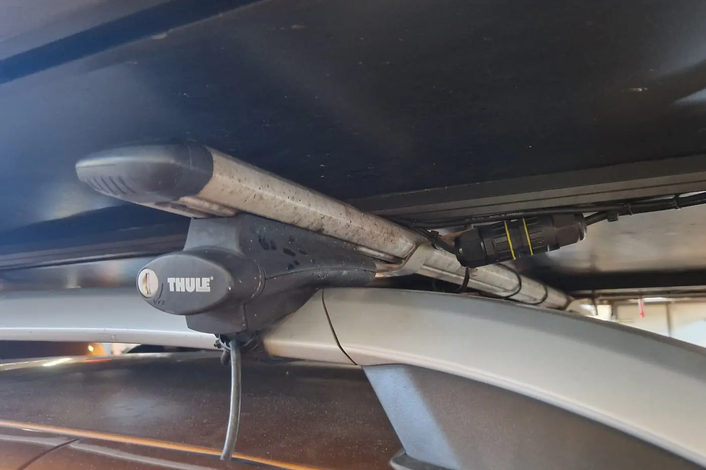 Blick unter ein Softshell-Dachzelt auf Querträger und Thule-Traegerfuesse auf der Dachreling