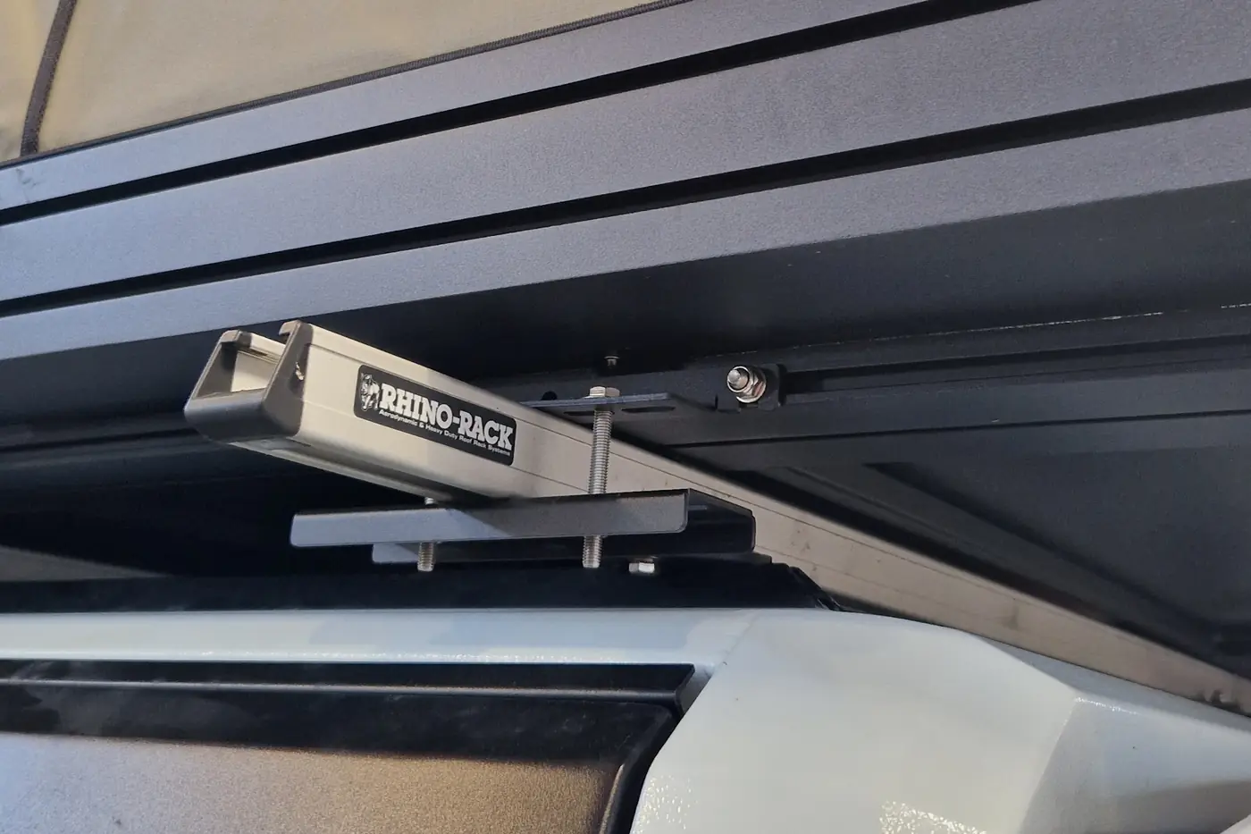 Rhino-Rack Plattformtraeger mit Befestigungskralle unter einem Hartschalen-Dachzelt im Detail